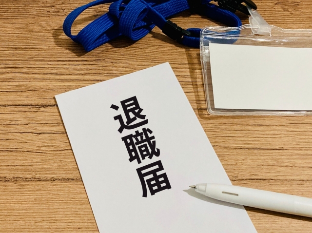 机に置かれた白い封筒の退職届とベンの写真