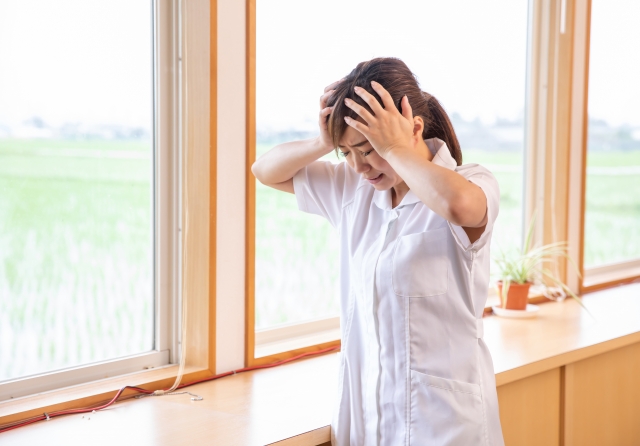 女性看護師が廊下で頭を抱える画像