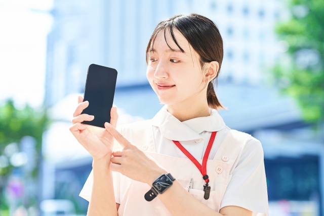 スマートフォンを笑顔で指さす女性看護師