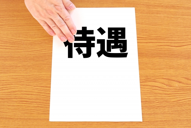 「待遇」と書かれた白い紙をテーブルに差し出すイラスト