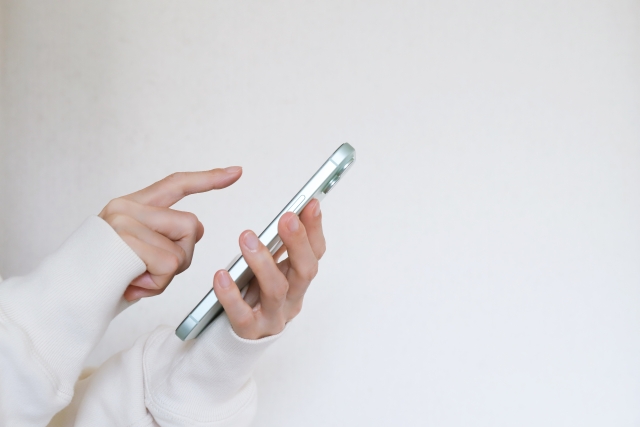 スマートフォンを操作する女性の手の画像