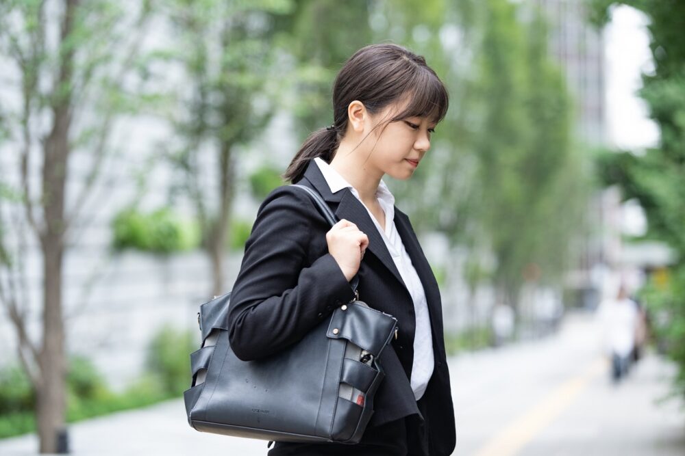 リクルートスーツを着たうつむく女性の画像