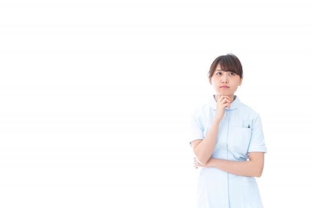 右手を顎にあてて考えるポーズの女性看護師の画像