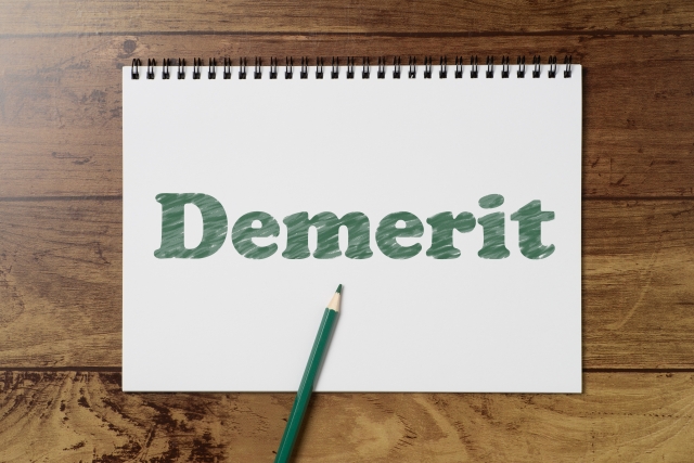 メモ帳に緑ペンで「Demerit」と書かれたイラスト
