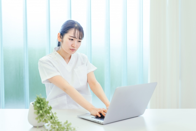 ノートPCの画面を見て困った表情をする女性看護師