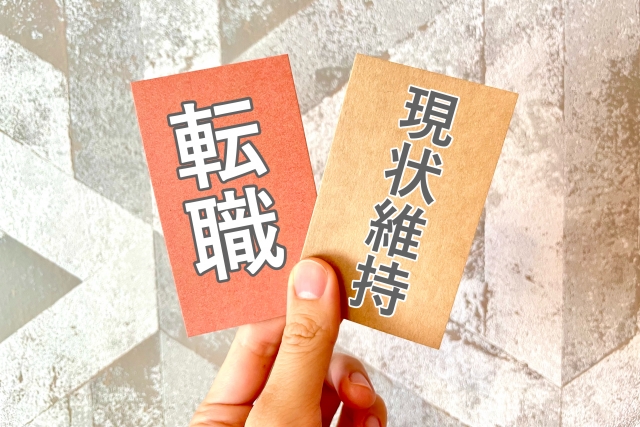 「転職」と「現状維持」の2つのカードを持つ手の写真