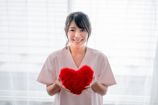 ハートを持って笑顔を見せる女性医療スタッフ
